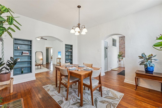 dining space featuring built in shelves, baseboards, arched walkways, and wood-type flooring