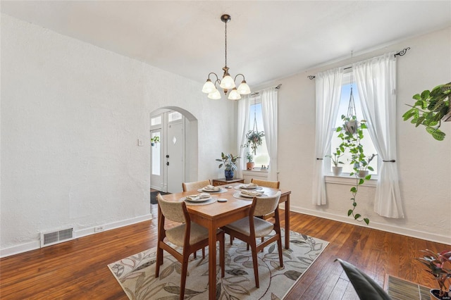 dining area with visible vents, baseboards, an inviting chandelier, arched walkways, and hardwood / wood-style flooring