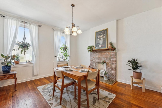 dining area featuring an inviting chandelier, hardwood / wood-style flooring, a brick fireplace, and baseboards