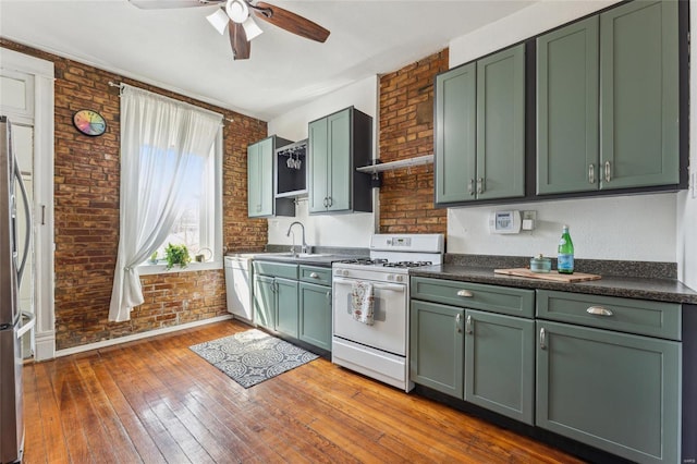 kitchen featuring ceiling fan, white range with gas stovetop, brick wall, and green cabinetry