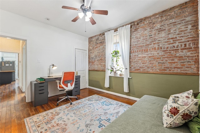 office featuring hardwood / wood-style floors, brick wall, wainscoting, and ceiling fan