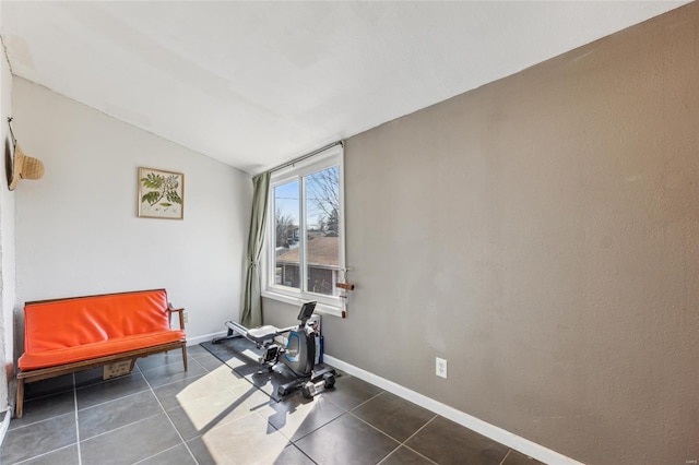 exercise area with tile patterned floors, baseboards, and lofted ceiling