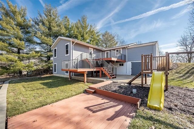 back of property featuring a wooden deck, a lawn, and a playground