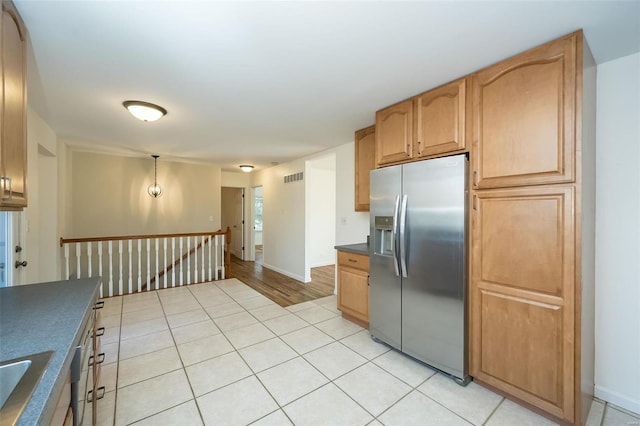 kitchen with stainless steel fridge, decorative light fixtures, sink, and light tile patterned floors