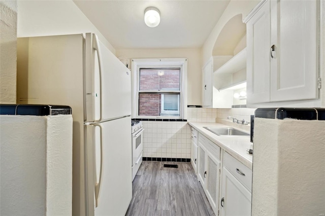 kitchen featuring sink, tile walls, white cabinets, white appliances, and light hardwood / wood-style flooring