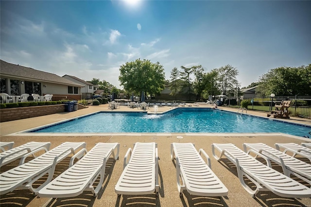 community pool with fence and a patio area