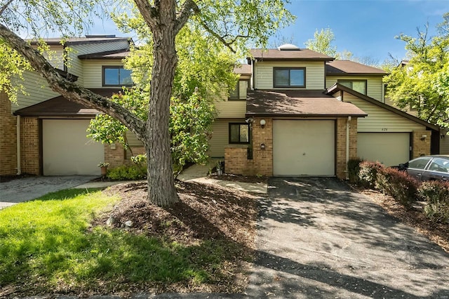view of front of property featuring brick siding, driveway, and a garage