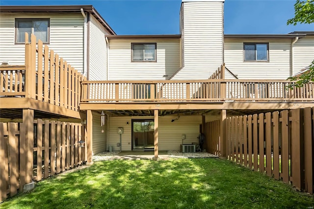 rear view of property with a chimney, a fenced backyard, a yard, cooling unit, and a wooden deck