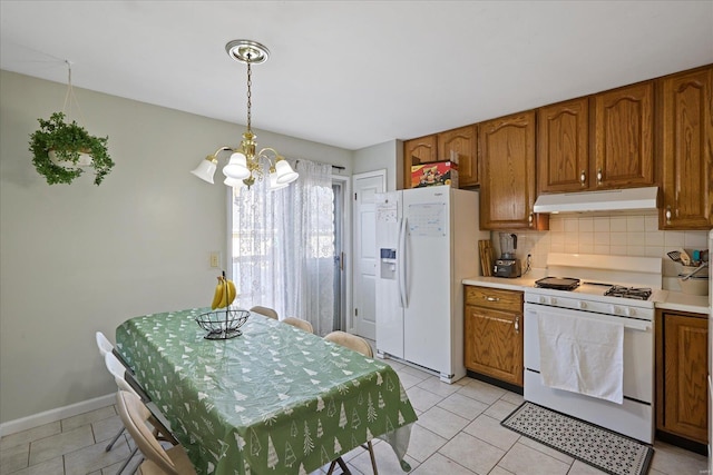 kitchen with tasteful backsplash, decorative light fixtures, a chandelier, light tile patterned floors, and white appliances