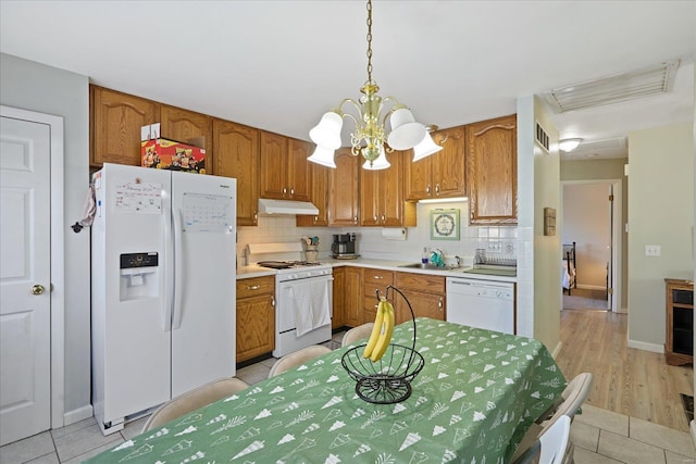 kitchen featuring sink, decorative light fixtures, a notable chandelier, white appliances, and backsplash