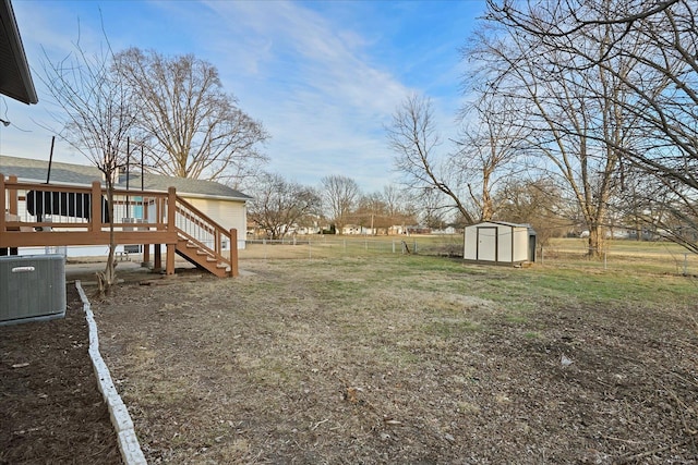 view of yard featuring central AC, a deck, and a shed