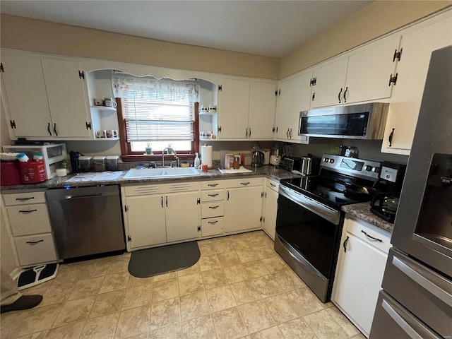 kitchen with white cabinetry, appliances with stainless steel finishes, sink, and dark stone counters