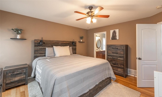 bedroom featuring ceiling fan, ensuite bath, and light hardwood / wood-style floors