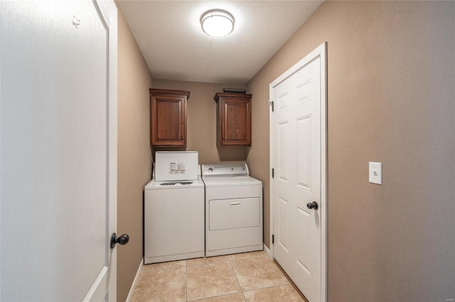 laundry room with light tile patterned flooring, cabinets, and washer and clothes dryer