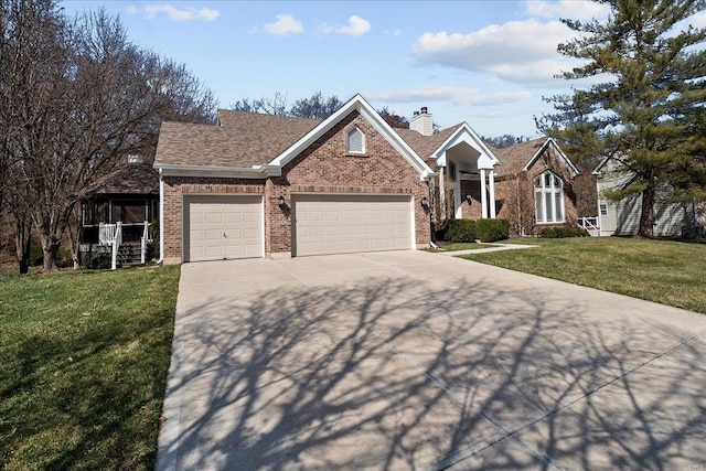 view of front facade featuring brick siding, a front yard, a chimney, driveway, and an attached garage