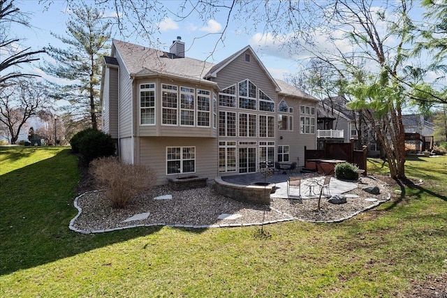 back of house featuring a jacuzzi, a lawn, a chimney, and a patio area