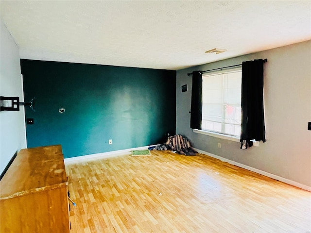 unfurnished room featuring baseboards, visible vents, and wood finished floors