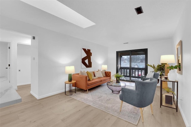 living room featuring a skylight and light hardwood / wood-style flooring