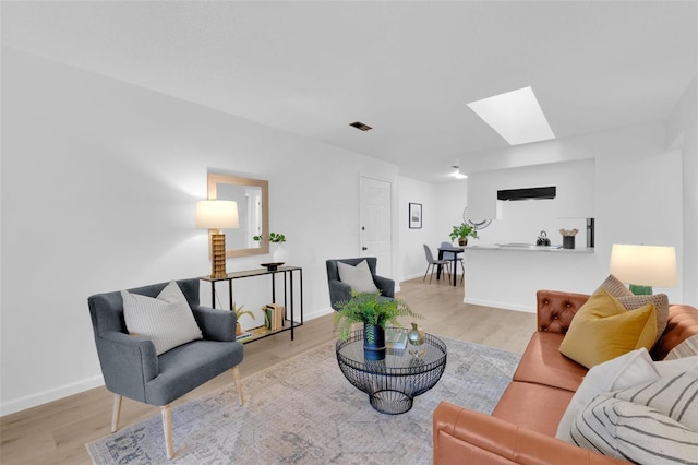 living room featuring light hardwood / wood-style floors and a skylight