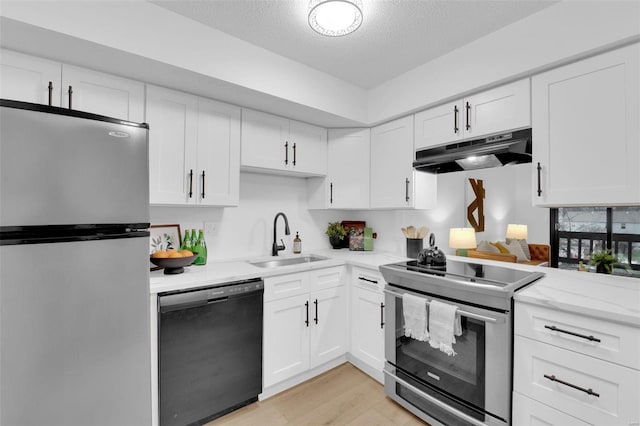 kitchen with appliances with stainless steel finishes, sink, white cabinets, a textured ceiling, and light hardwood / wood-style flooring