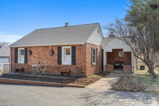 view of front of house featuring brick siding and roof with shingles