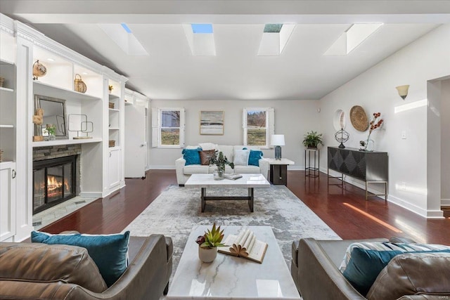 living room featuring a skylight, a fireplace, dark wood-style flooring, and baseboards