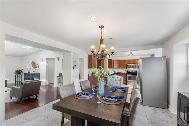 dining space featuring built in shelves, baseboards, recessed lighting, light wood-style floors, and a notable chandelier