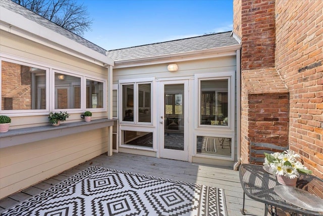 doorway to property with roof with shingles and a deck