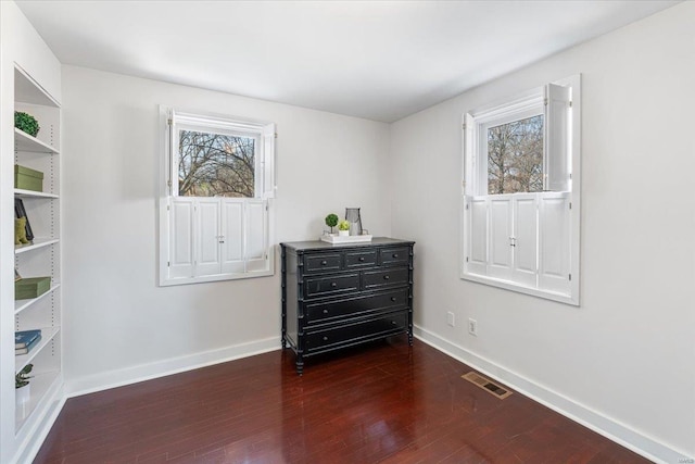 interior space featuring multiple windows, baseboards, visible vents, and dark wood-style flooring