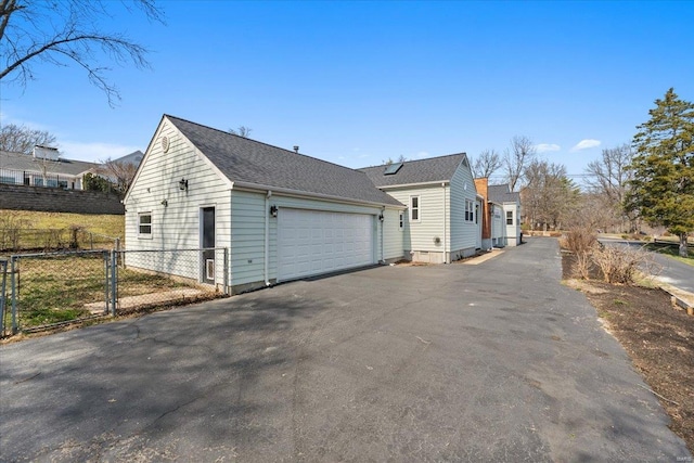 view of side of property with an attached garage, fence, and driveway