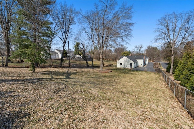 view of yard featuring a garage, aphalt driveway, and fence