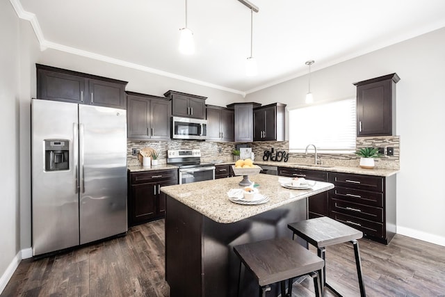 kitchen featuring sink, appliances with stainless steel finishes, dark hardwood / wood-style floors, a kitchen island, and pendant lighting