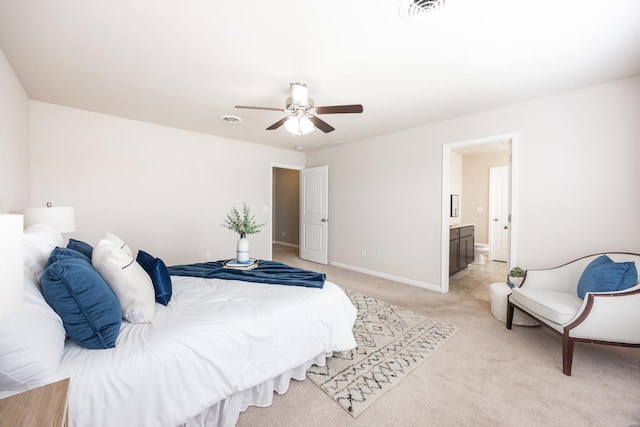 bedroom with ceiling fan, ensuite bath, and light carpet