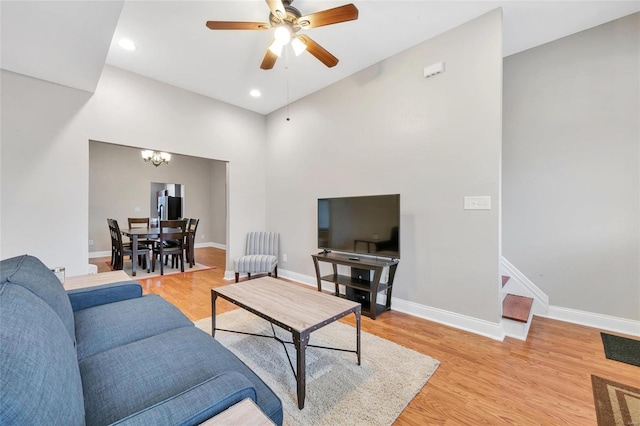 living room with ceiling fan with notable chandelier and light hardwood / wood-style floors