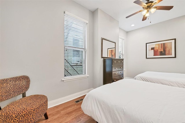 bedroom with hardwood / wood-style flooring, ceiling fan, and multiple windows