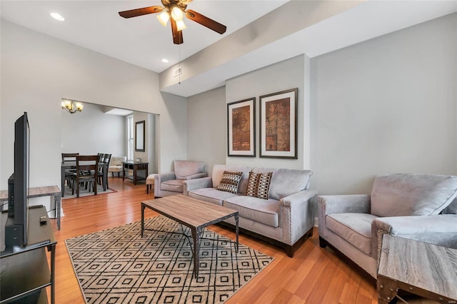 living room featuring ceiling fan with notable chandelier and light hardwood / wood-style flooring