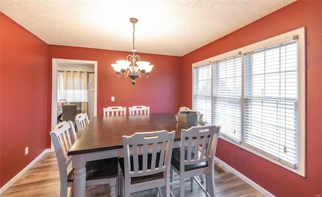 dining space with hardwood / wood-style floors, a textured ceiling, and a chandelier