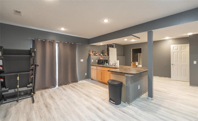 kitchen featuring light hardwood / wood-style floors, kitchen peninsula, and light brown cabinets