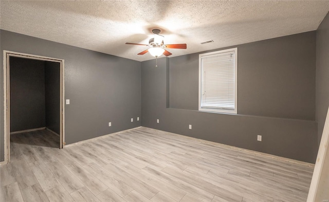 empty room with a textured ceiling, light hardwood / wood-style flooring, and ceiling fan