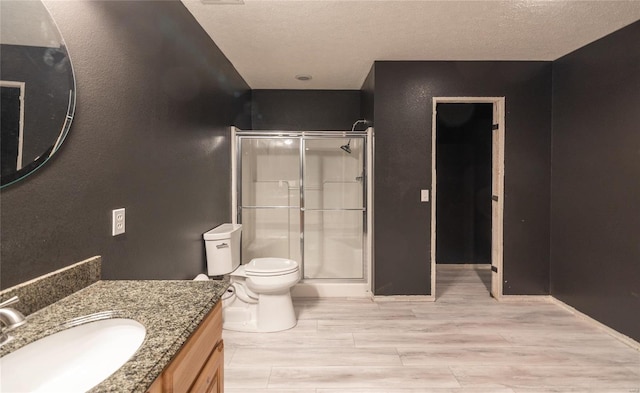 bathroom with walk in shower, vanity, toilet, and a textured ceiling