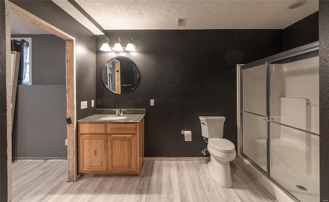 bathroom featuring hardwood / wood-style flooring, vanity, a textured ceiling, toilet, and walk in shower