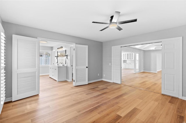 unfurnished living room featuring sink, light hardwood / wood-style flooring, and ceiling fan