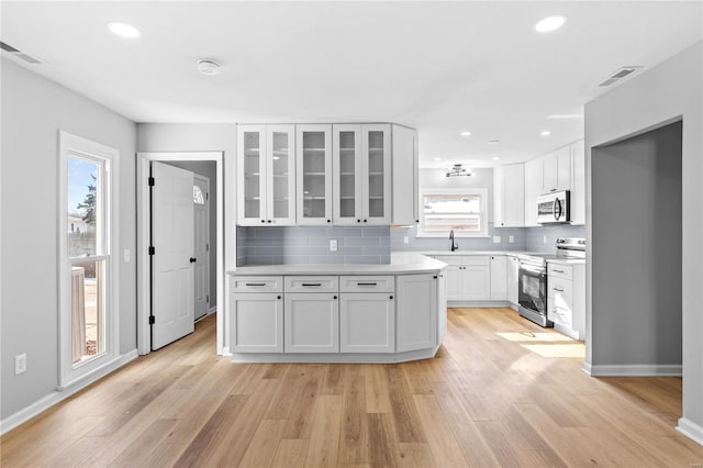 kitchen with sink, stainless steel appliances, light hardwood / wood-style floors, white cabinets, and decorative backsplash