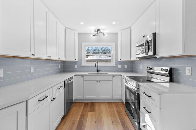 kitchen with sink, white cabinetry, tasteful backsplash, light hardwood / wood-style flooring, and stainless steel appliances