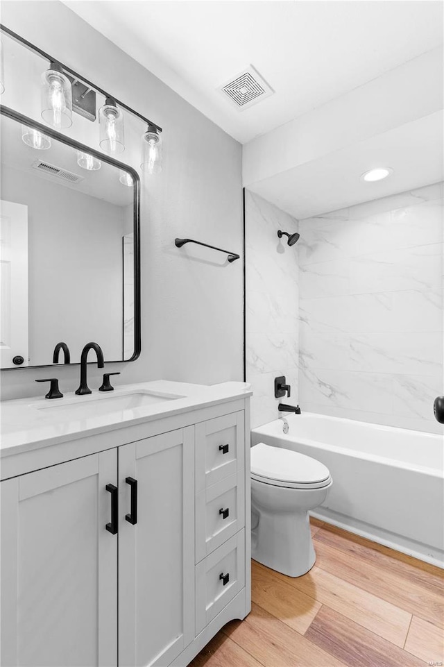 full bathroom with vanity, tiled shower / bath, wood-type flooring, and toilet