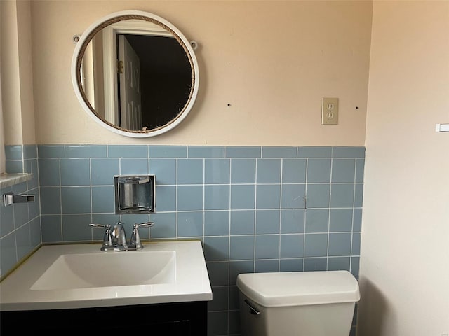 bathroom featuring vanity, tile walls, and toilet