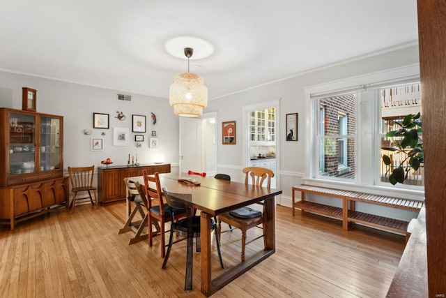 dining space with light wood-style flooring, visible vents, and baseboards