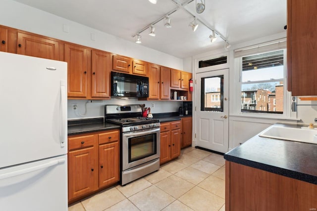 kitchen featuring black microwave, a sink, stainless steel range with gas cooktop, freestanding refrigerator, and dark countertops