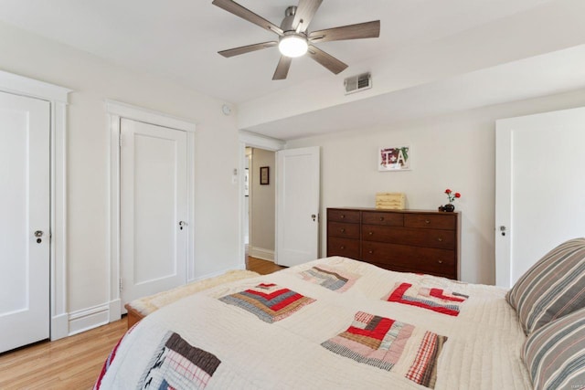 bedroom with ceiling fan, light wood finished floors, and visible vents