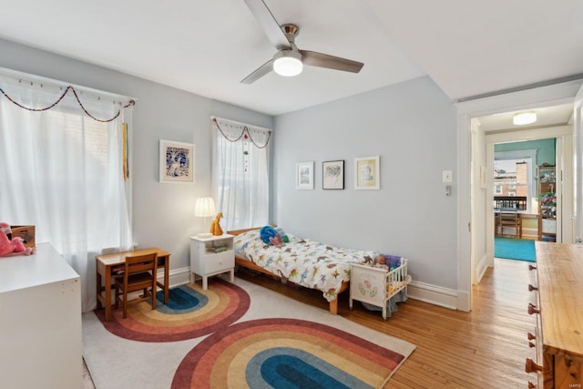 bedroom with light wood finished floors, multiple windows, and baseboards